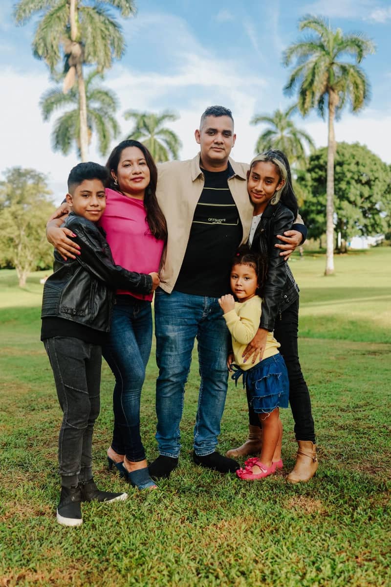 Familia latina sonriente reunida al aire libre entre palmeras