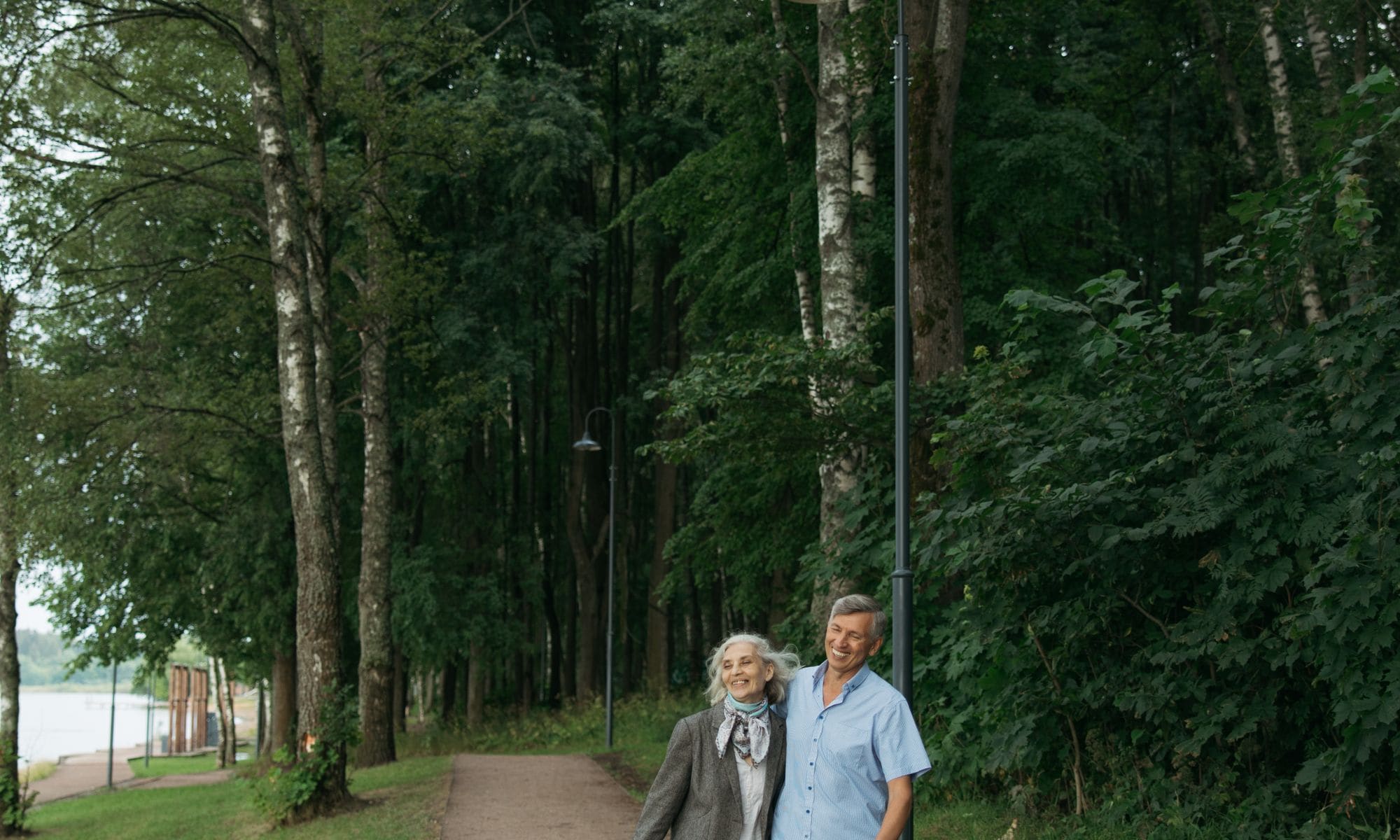 Pareja adulta mayor caminando y sonriendo en un parque