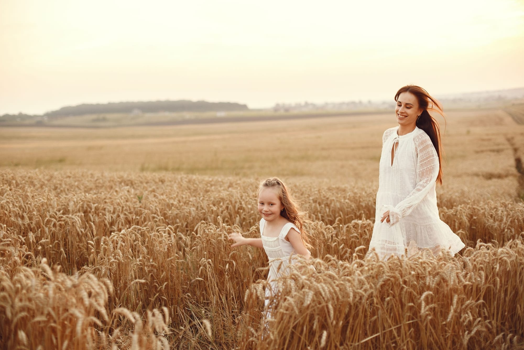 Madre e hija corriendo por un campo al atardecer